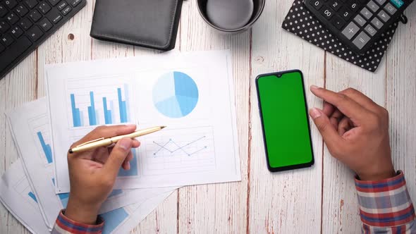 Top View of Man Hand Using Smart Phone and Analyzing Financial Data