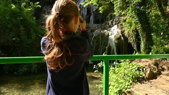 Girl is taking pictures of a beautiful waterfall