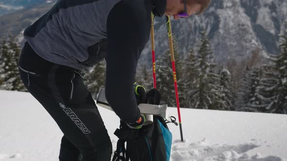 Man In Skiwear Putting Glide Tape From His Skis Into Backpack