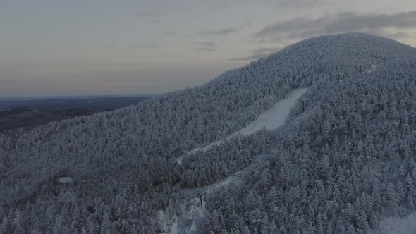 Abandonded ski lift at the peak of a snow covered mountain AERIAL PULL BACK