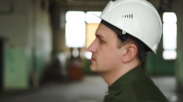 Inspector in Helmet Walks Along the Corridor of an Old Building Looks Around