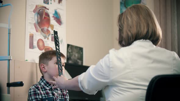 A Treatment in Eye Clinic - a Woman Doctor Checking an Eye Visibility of a Little Boy Using