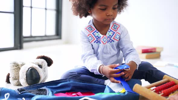 Cute Little African American Girl in Casual Clothing Playing Around with a Clothing in Room at Home