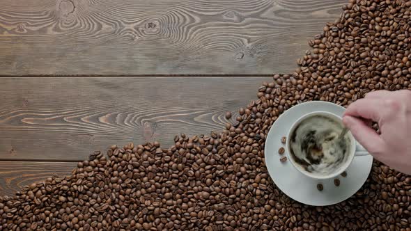 Caucasian Hand Stirring Black Frothy Coffee and with a Spoon