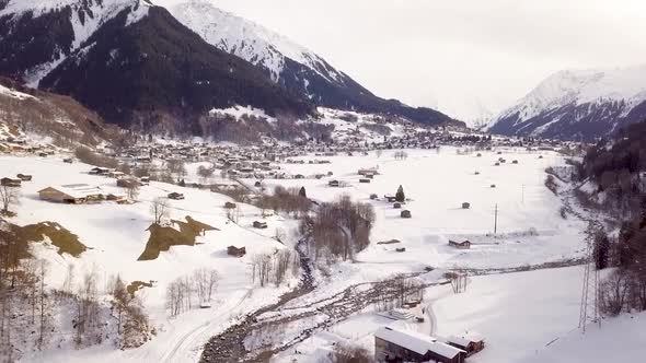 Drone shot of a village in the winter. In the foreground is a river.
