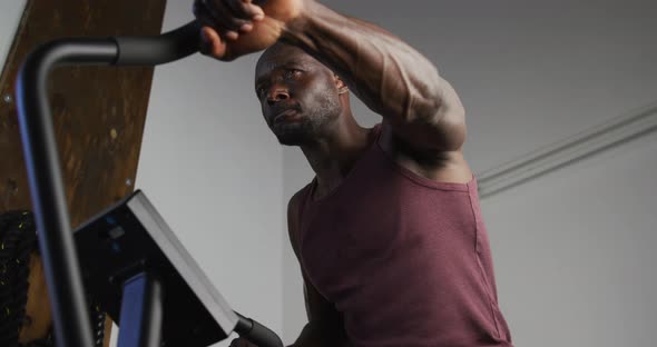 Fit african american man exercising on training bike inside gym