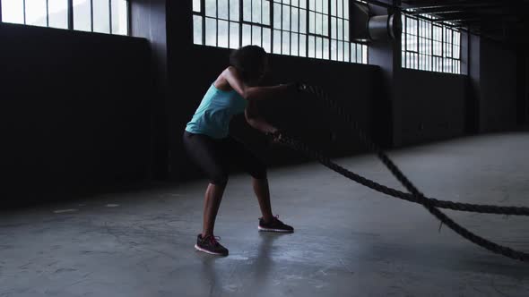 African american woman exercising battling ropes in an empty urban building
