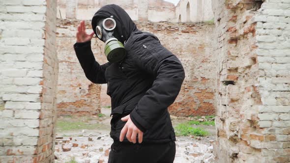 Man in gas mask and black clothes runs on an abandoned ruined building. Stalker concept
