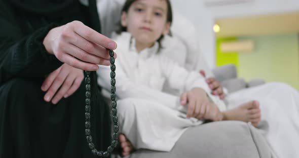 Muslim Woman Praying at Home with Kid in Background