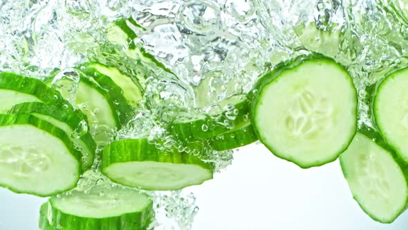 Super Slow Motion Shot of Cucumber Slices Falling Into Water on White Background at 1000Fps.