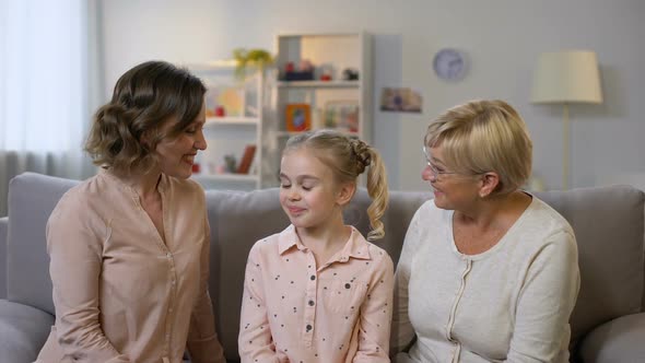 Loving Mother and Granny Kissing Daughter Cheeks and Hugging, Female Generations