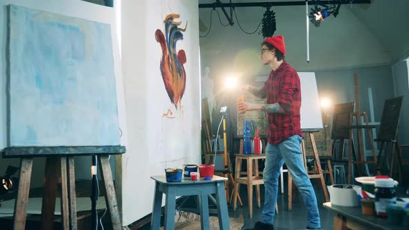 Male Painter is Sprinkling a Picture with Paints