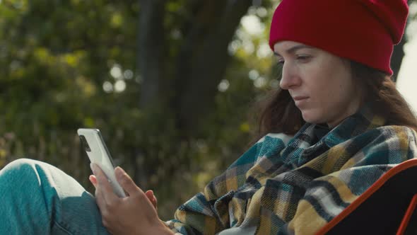 Female use mobile phone while sitting on camping chair