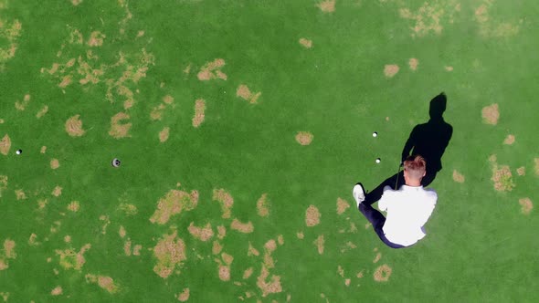 Man Puts Ball in a Hole While Playing Golf on a Course