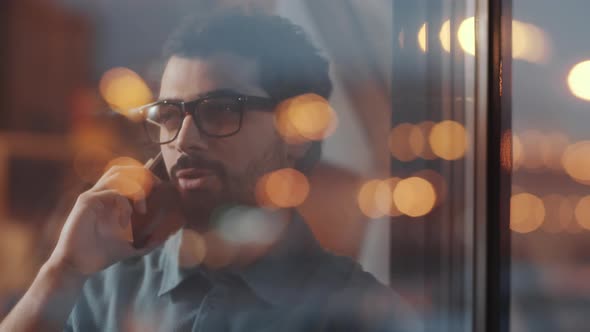 View through Glass Wall of Middle Eastern Businessman Speaking on Phone