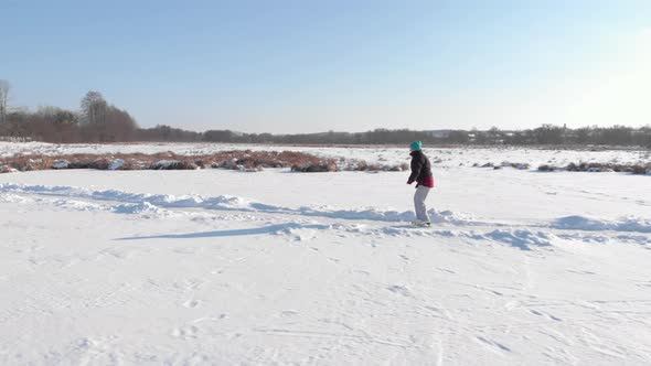 Female in casual wear is skating outdoor on frozen lake in winter