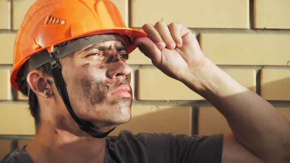 Dirty Building Worker Background Brick Wall. Handsome Serious Man in Hard Hat