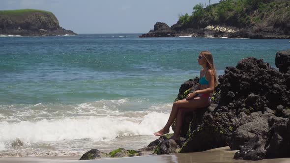 Girl Sits on the Rock and Looks at the Sea. Bali, Indonesia