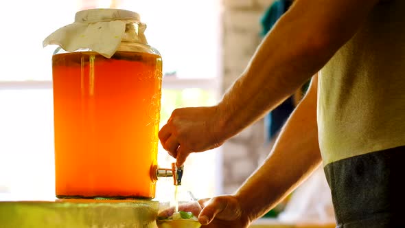 Caucasian man pours brewed kombucha from container, probiotic drink