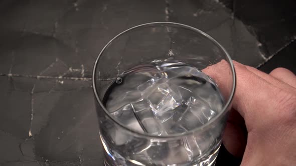 Glass with water rotating at wooden table. 