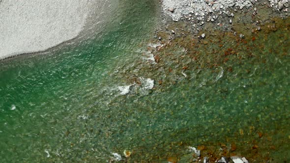 Descending rotating aerial view of fast flowing green river in Blue Pools in New Zealand