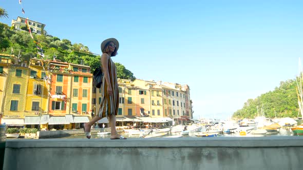 A woman walking wearing hat and backpack purse traveling, Portofino, Italy, luxury resort, Europe