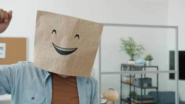 Slow Motion Portrait of Cheerful Employee Wearing Breadbag with Emoji on Head Dancing in Office