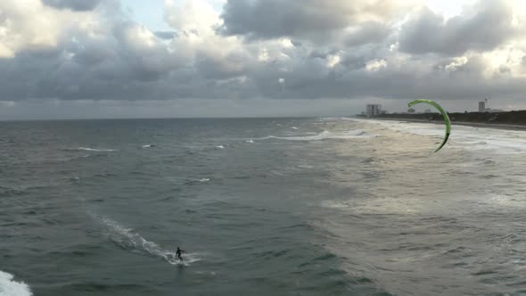 cinematic aerial video of kiteboarder riding towards the shore