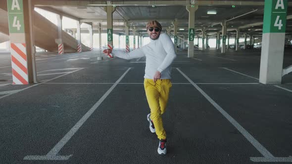 Cheerful and Happy Young Man with Beard Actively Is Dancing While Walking Down the Street on Urban