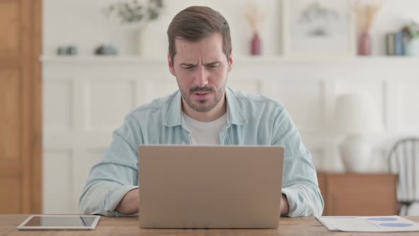 Young Man Coughing While Using Laptop in Office