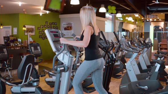 Young and Sexy Girl is Running on a Stepper at the Gym