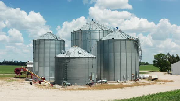 Industrial agricultural farming grain bin silos on countryside farm. Blue sky clouds