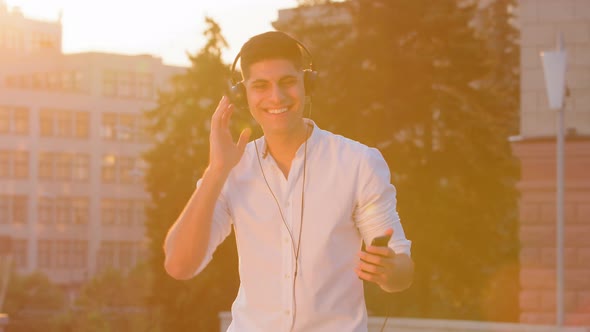 Happy Middle Eastern Young Man in White Shirt Enjoy Good Quality Sound in Headphones Smiling Indian