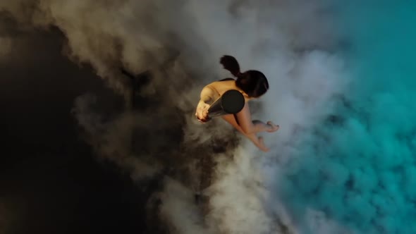 Dancer Spins on a Pole in Blue Smoke and Performs Tricks . Slow Motion. Top View