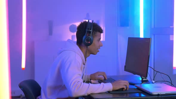 Profile View of Young Gammer in Headphones Playing in Online Shooter