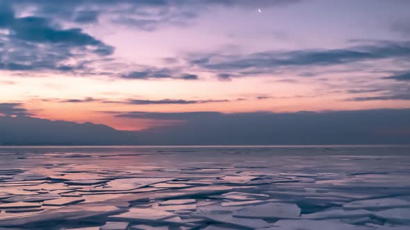 Rafted ice on a frozen lake, mountains and cloudscape - time lapse zoom out