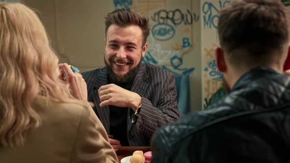 Handsome stylish guy drinks filter coffee in a coffee shop in the company of cheerful friends.