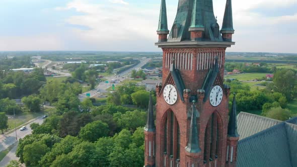 Church in Small City Among Pastures. Drone Footage. Red Church Is Roman Catholic Church.