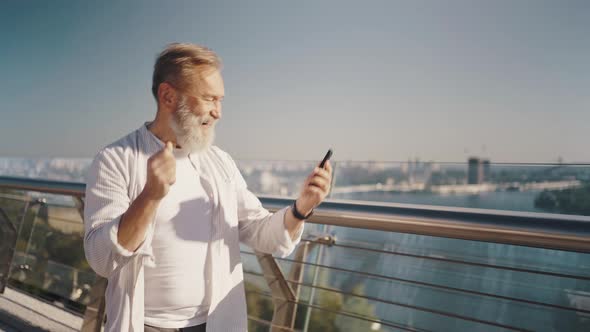 Pensioner Walks on Footbridge Listening to Music on Phone