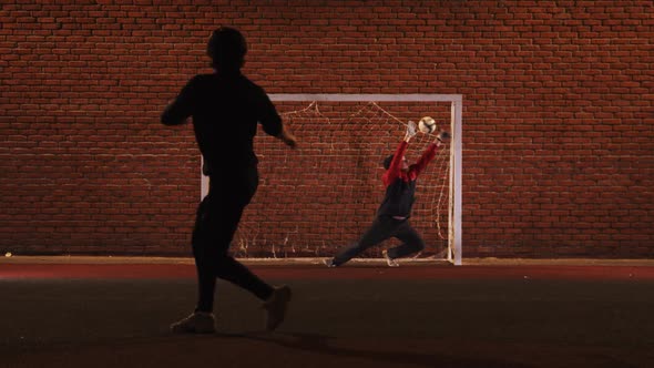 Two Young Men Friends Playing Football on the Outdoor Playground at Night - Protecting the Football