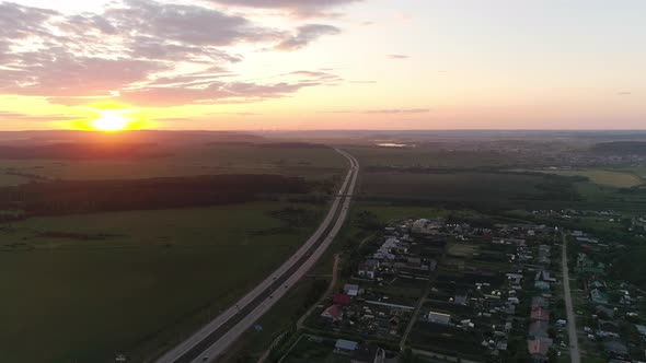 Aerial view of evening highway at sunset near the village and field 02