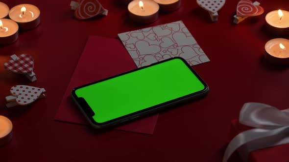 Top View of Smartphone with Green Screen Chroma Key on Red Table with Burning Candles Hearts