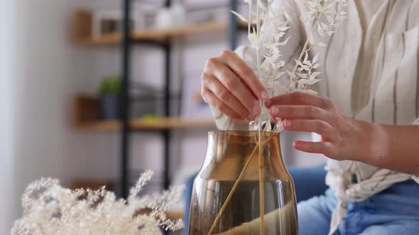 Woman Arranging Dried Flowers in Vase at Home