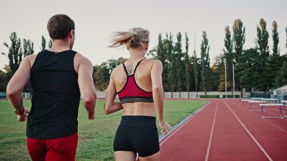 Rear View of a Couple a Guy and a Girl Have an Outside Running Workout at the City Stadium
