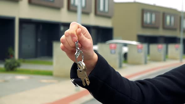 A Woman Clinks Her Key in a Suburban Area, Buildings in the Background - Closeup on the Hand