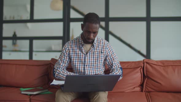 Busy African Man Working on Laptop on Sofa