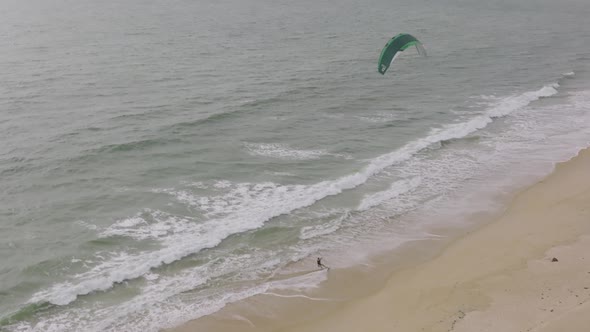 Wind surfer riding up onto the beach and jumping off the board on a beach in Sierra Leone Africa.