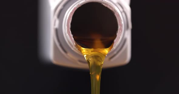 Yellow Transparent Oil Pouring From Plastic Bottle on Black Background