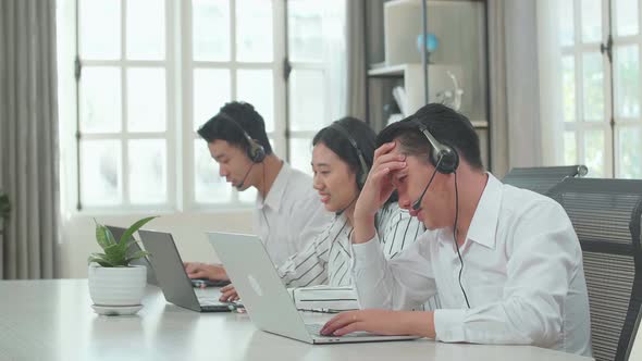 A Man Of Three Asian Call Centre Agents Headache While His Colleagues Are Speaking To Customers