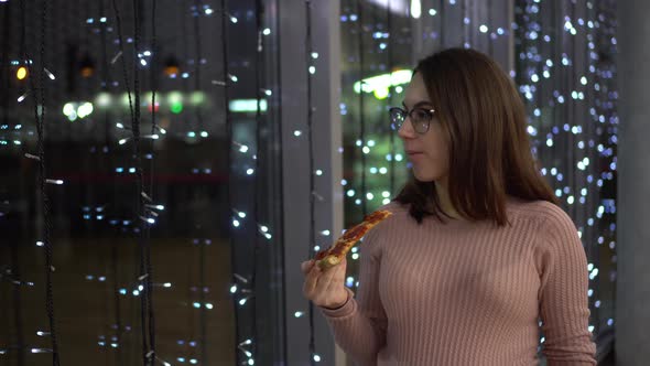 Young Woman with Glasses Eating Pizza